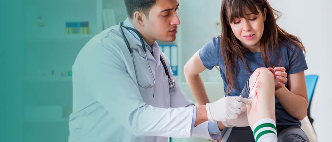 A doctor treats a woman’s injured knee