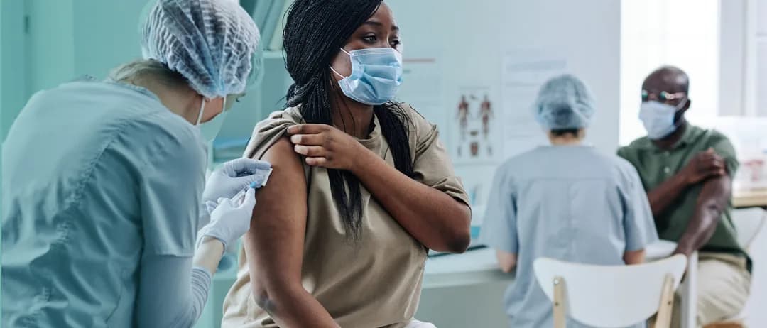 A patient receives a vaccination at a busy clinic